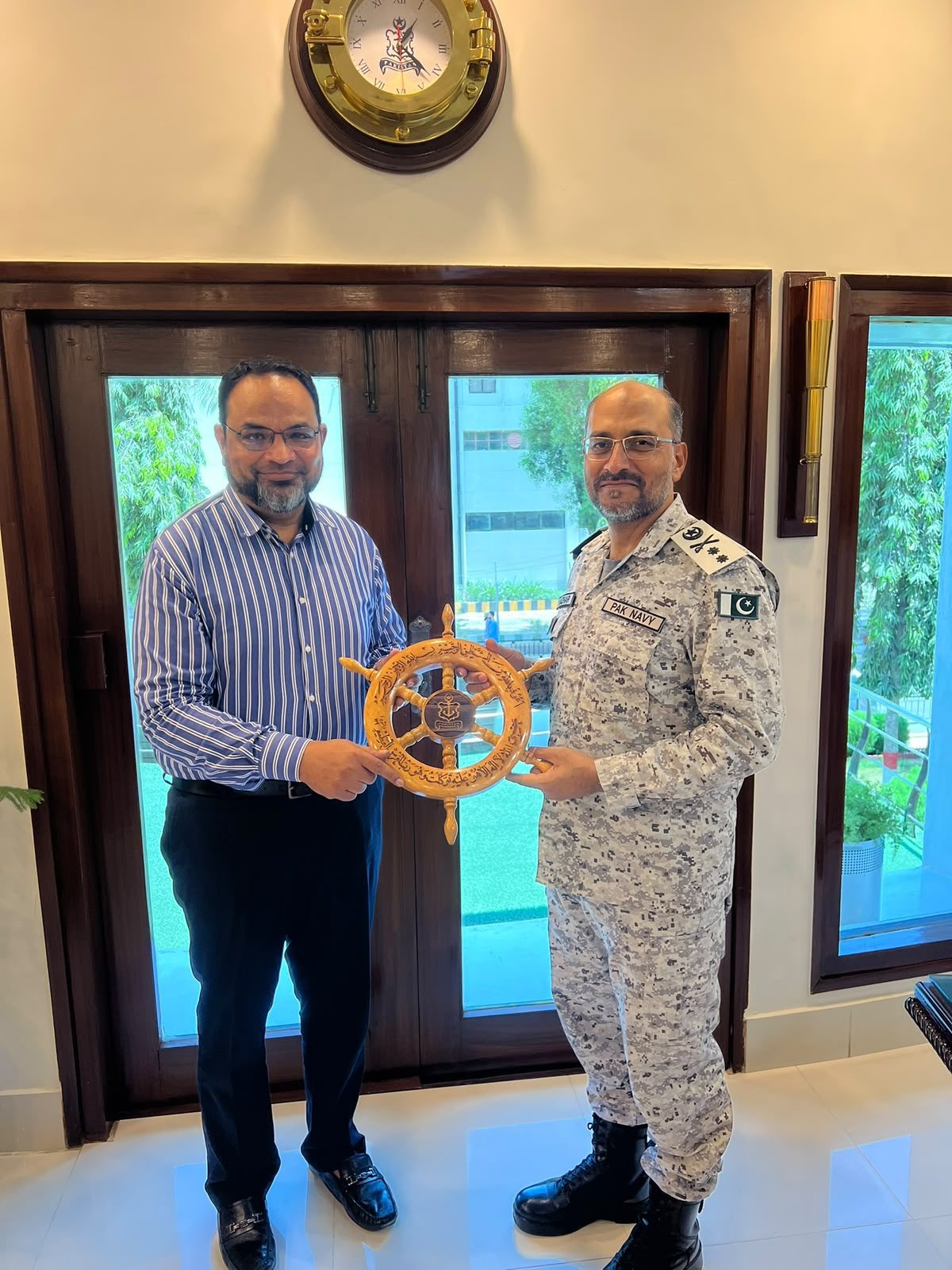 Mastoor Group — presenting a ceremonial ship's wheel memento to a Pakistan Navy officer